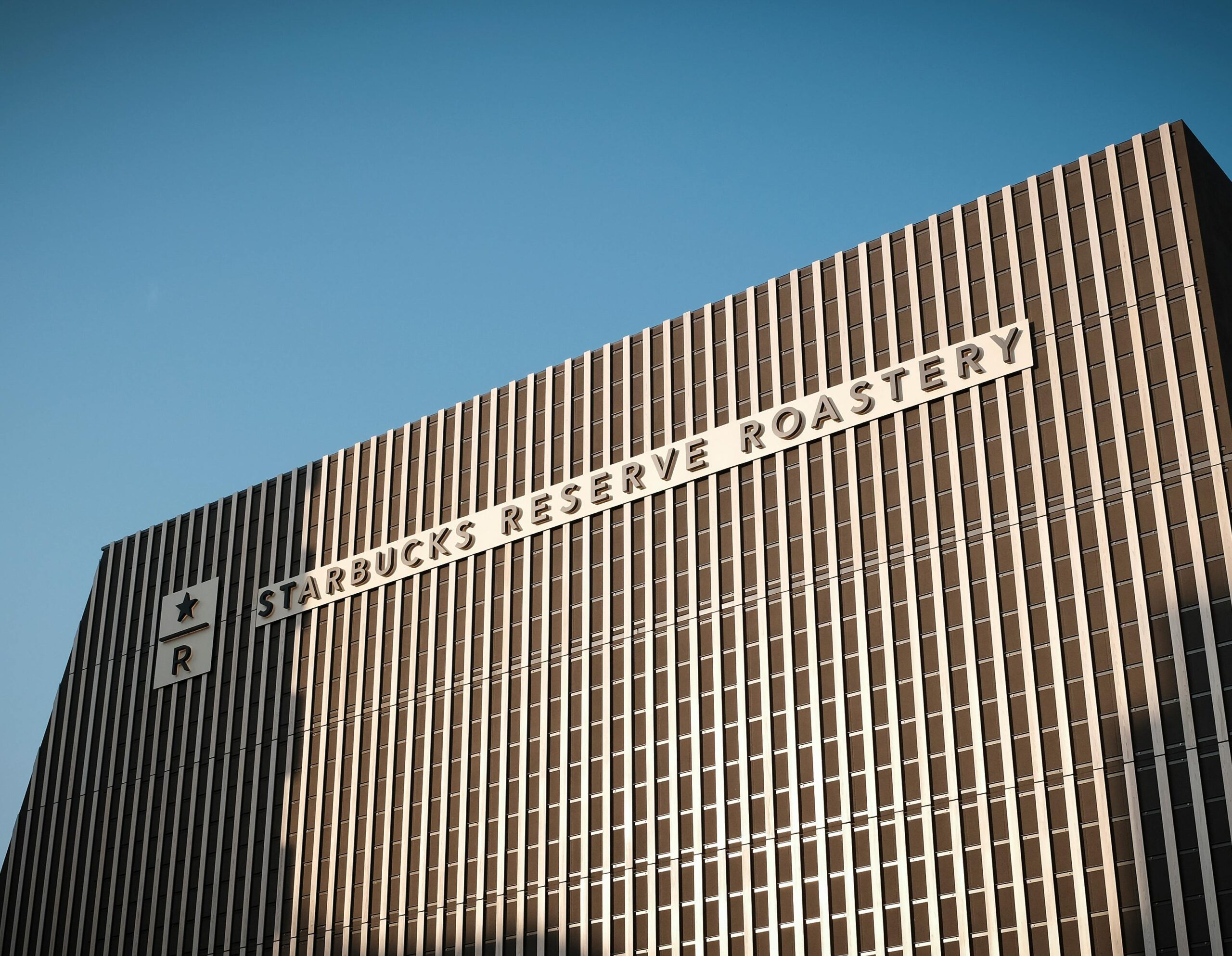 Exterior view of Starbucks Reserve Roastery in Tokyo showcasing modern design against blue sky.